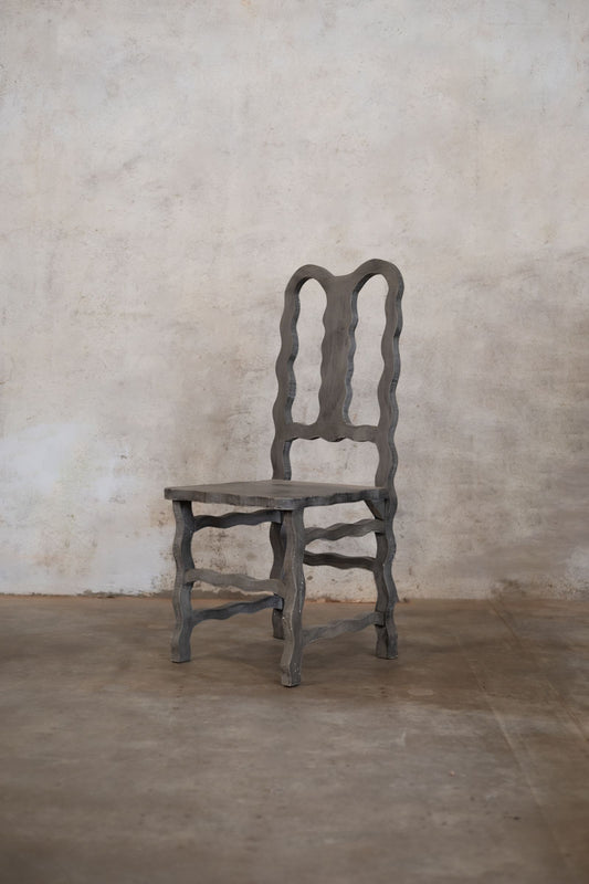 Decorative wooden chair against a textured beige wall.
