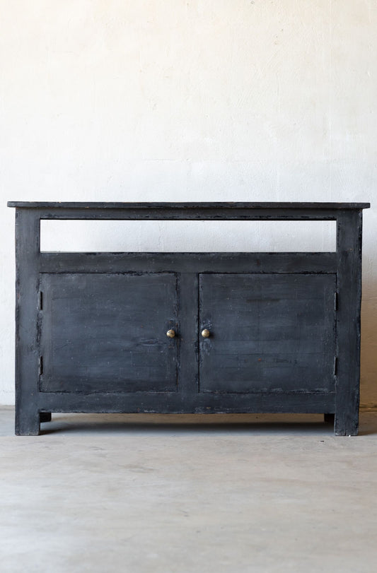 Dark wooden console table with two doors on a light gray floor and white wall background.