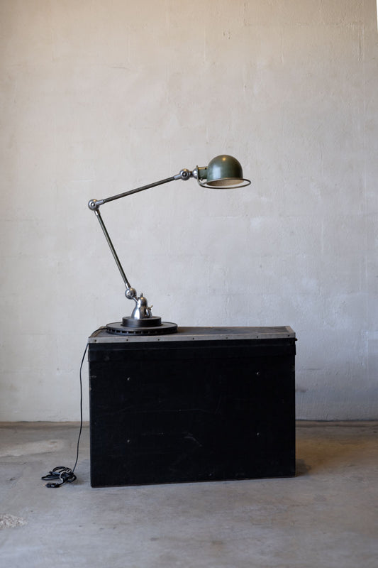 Vintage Jielde industrial desk lamp on a black metal cabinet against a plain wall.