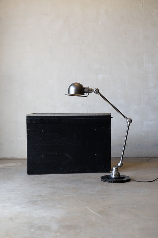 Vintage Jielde task lamp with long arm next to a black rectangular object on a plain background