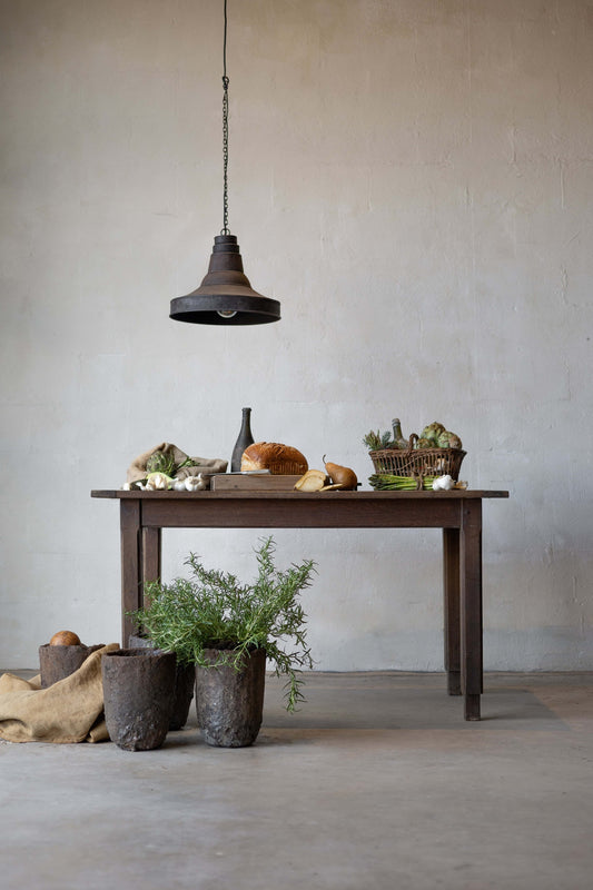 A dark oak table laden with food, an industrial lamp hanging above it.