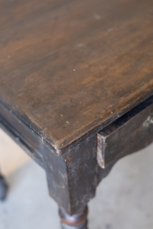 Close-up of the top of a vintage teak wood colonial desk with a worn surface