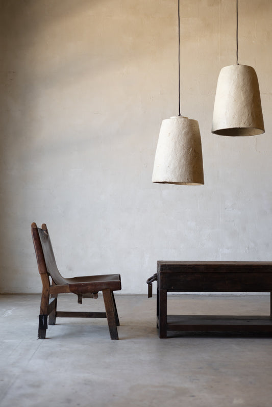 Minimalist interior with wooden chair and table under two white pendant lights.