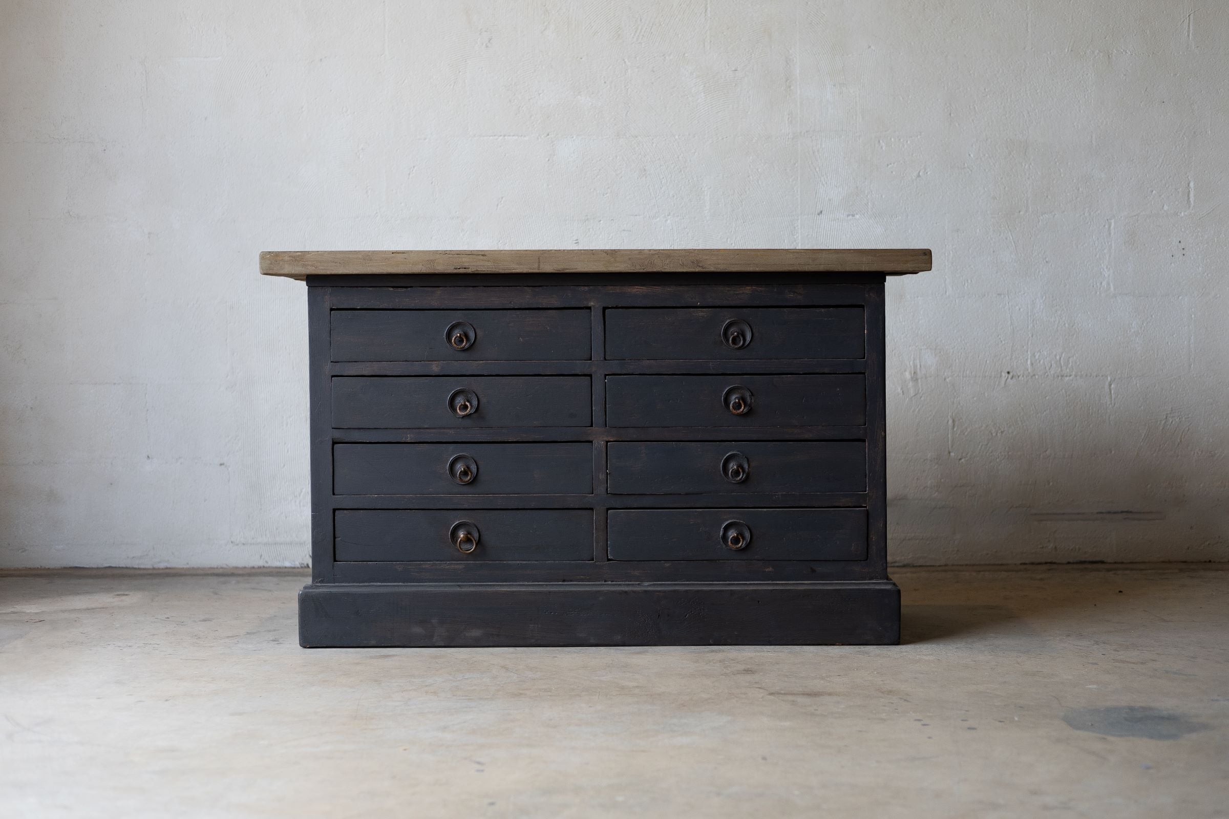 Dark wooden sideboard with multiple drawers against a plain wall.