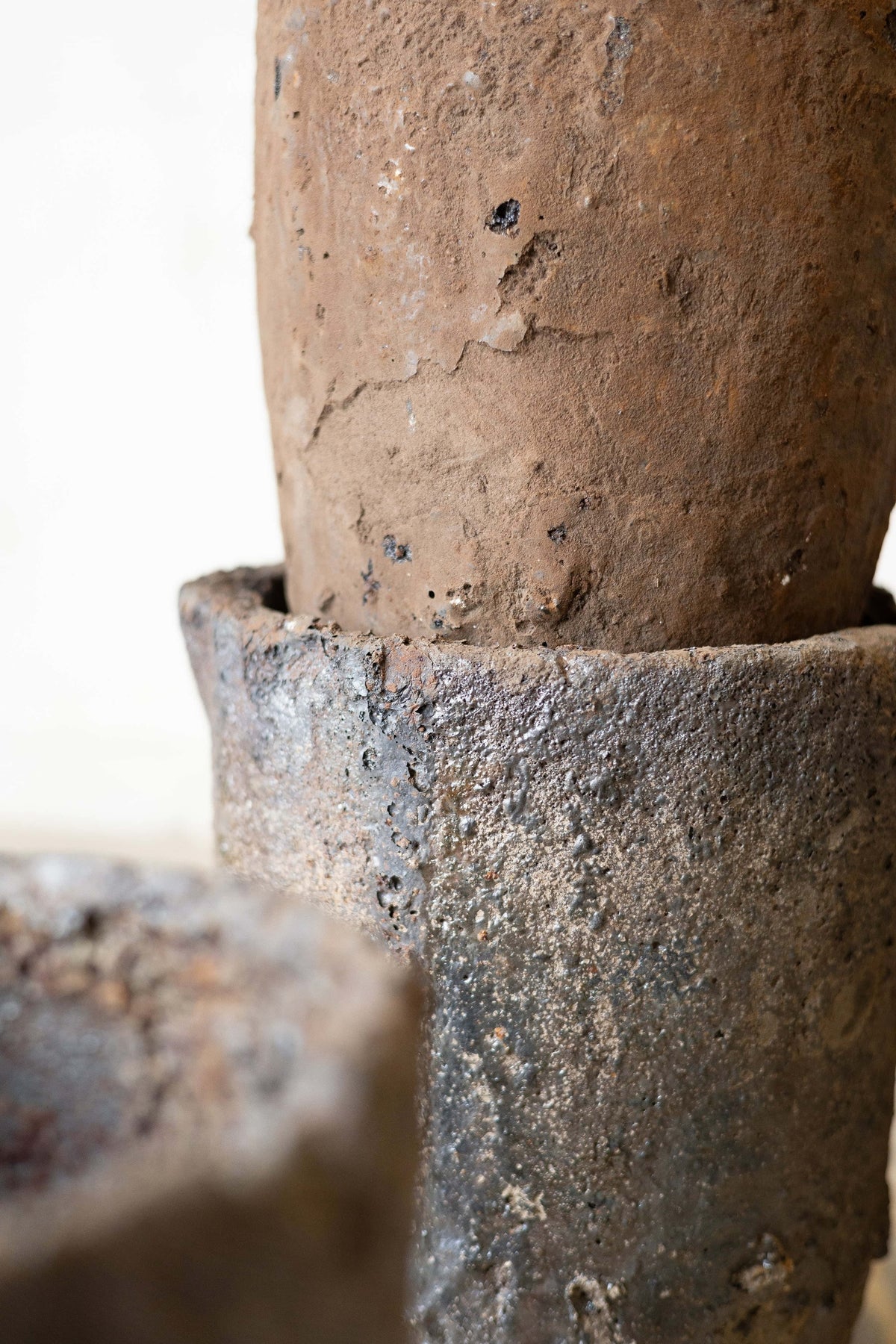 Two stacked foundry crucibles with a thick patina and rich, earth color.