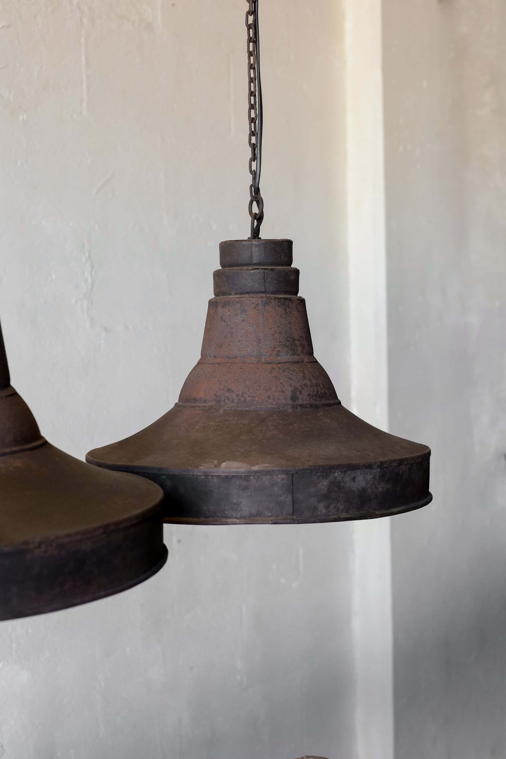 A pair of black pendant lights in industrial style, featuring natural patina and chain cord.