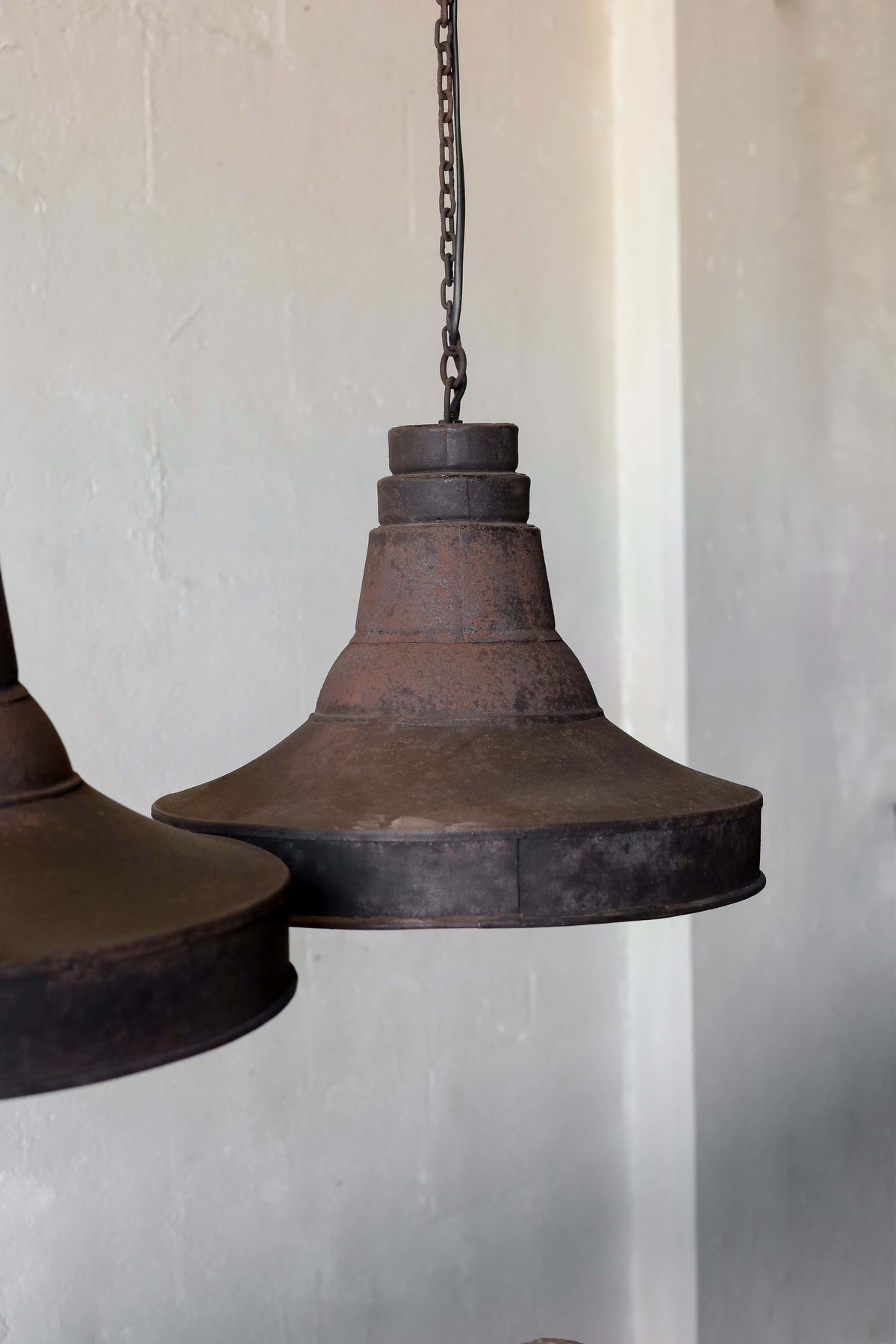A pair of black pendant lights in industrial style, featuring natural patina and chain cord.