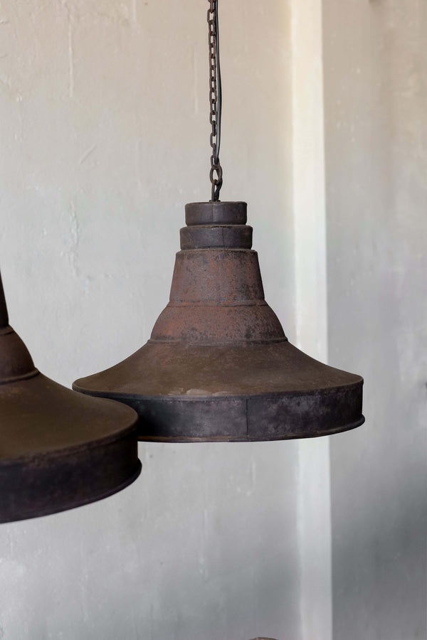 A pair of black pendant lights in industrial style, featuring natural patina and chain cord.