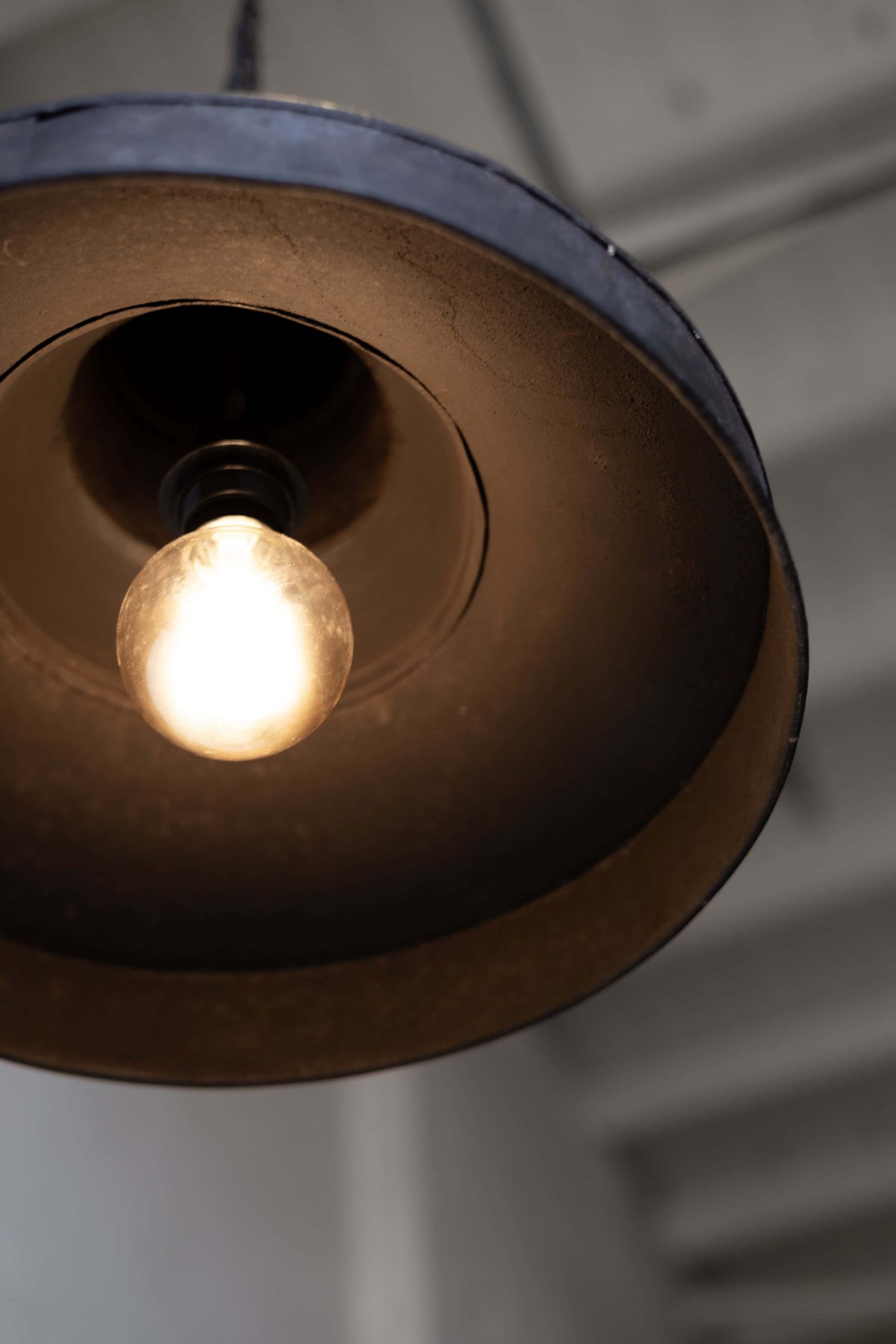 Underside of black pendant light, featuring a single bulb at the center. 