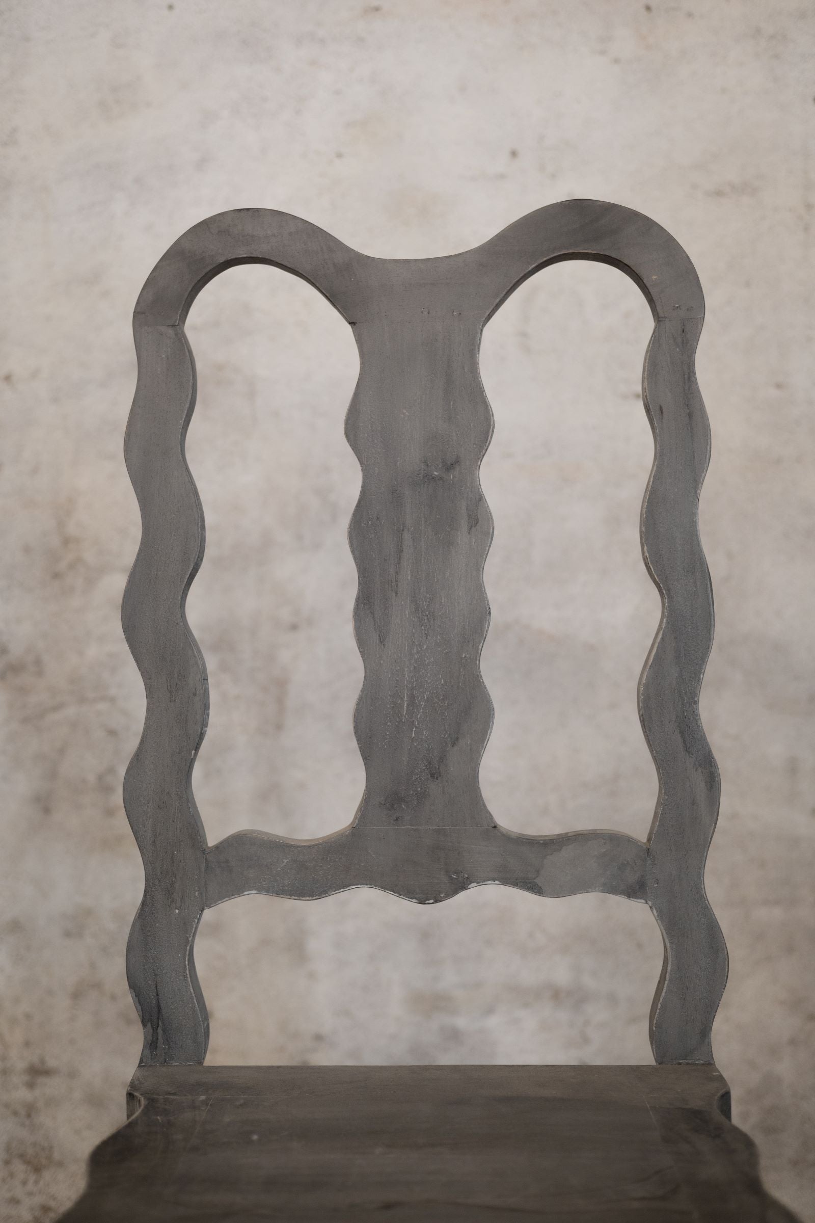 Vintage chair with decorative backrest against a textured wall