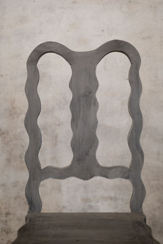 Vintage chair with decorative backrest against a textured wall