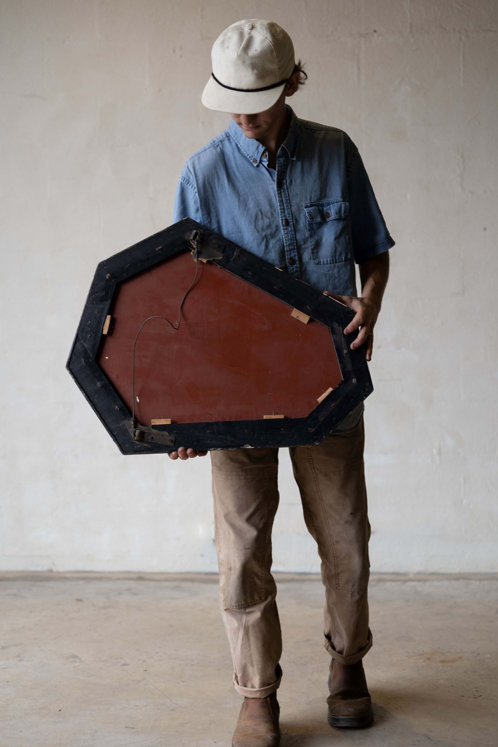 Image of a man holding the Venetian crystal mirror to show the well preserved back of the mirror and frame.