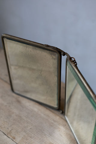 Vintage compact mirror with brass frame on a wooden surface