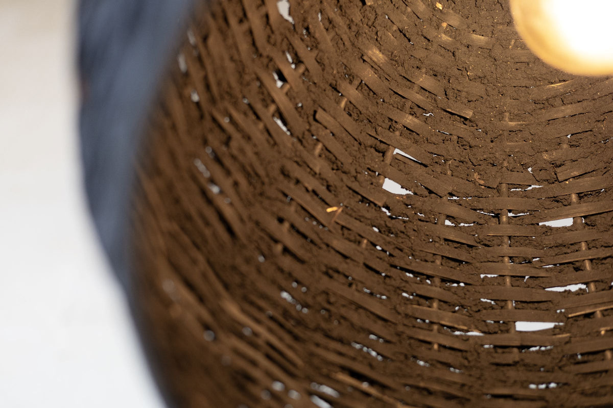 Offset close up of the inside of the black woven beehive pendant with warm light. 