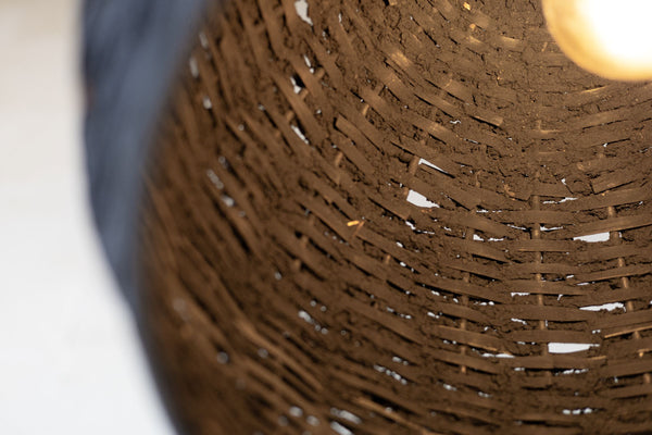 Offset close up of the inside of the black woven beehive pendant with warm light. 
