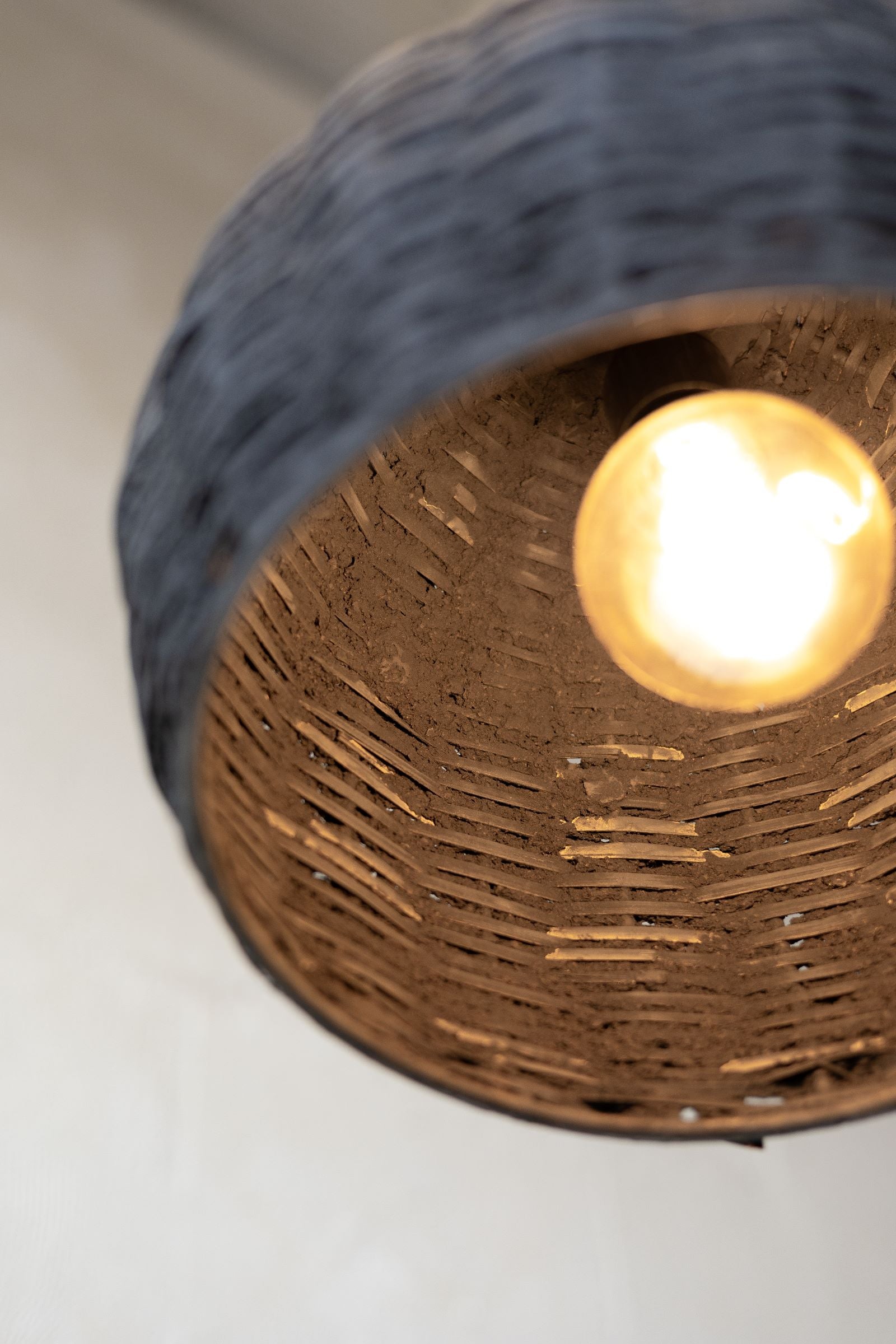 Offset picture of the inside of the black woven beehive pendant with warm light. 