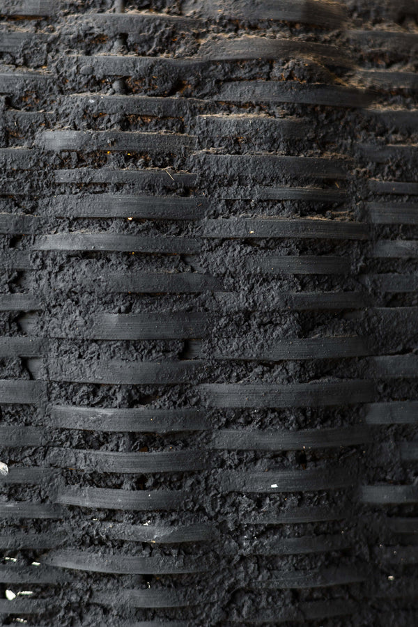 Close up of black woven beehive pendant showing the rustic texture of the clay and woven fibers.