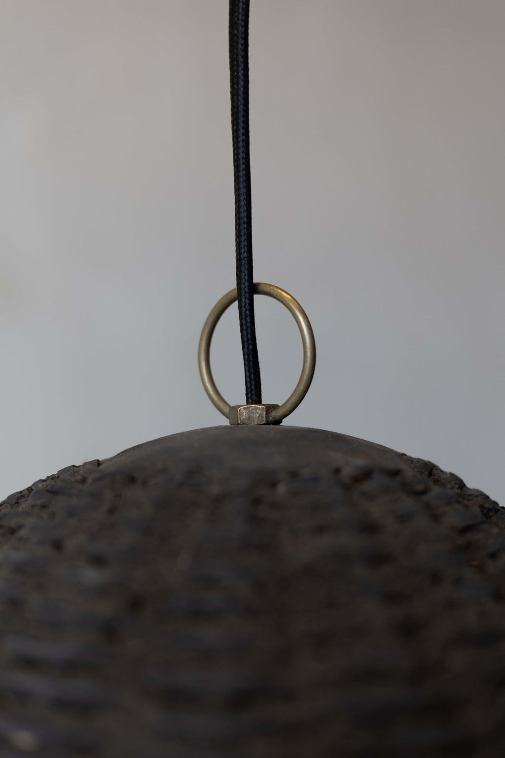 Close up of the top of the black woven beehive pendant with black woven wire and brass loop. 