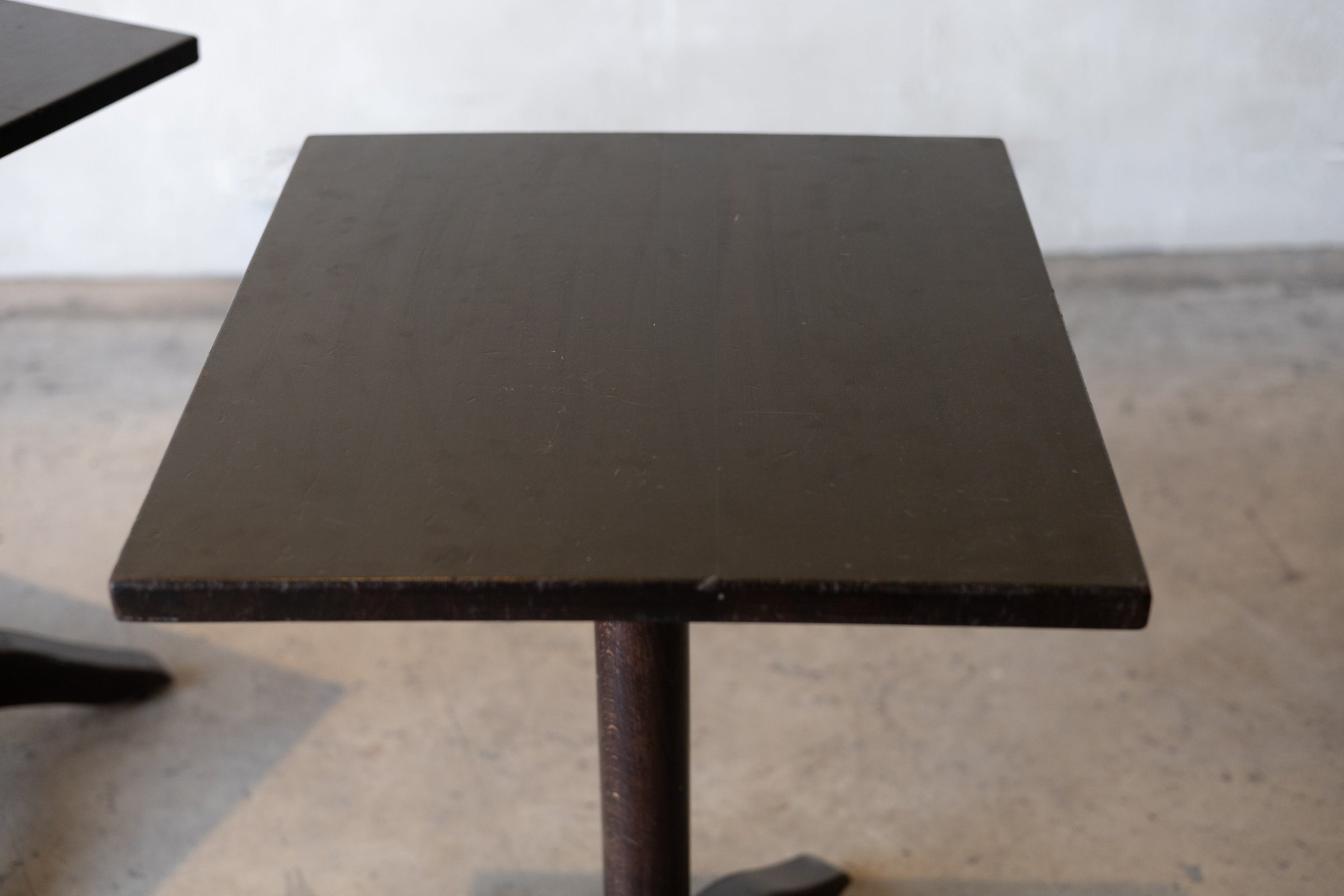 Square dark brown table on a plain background.