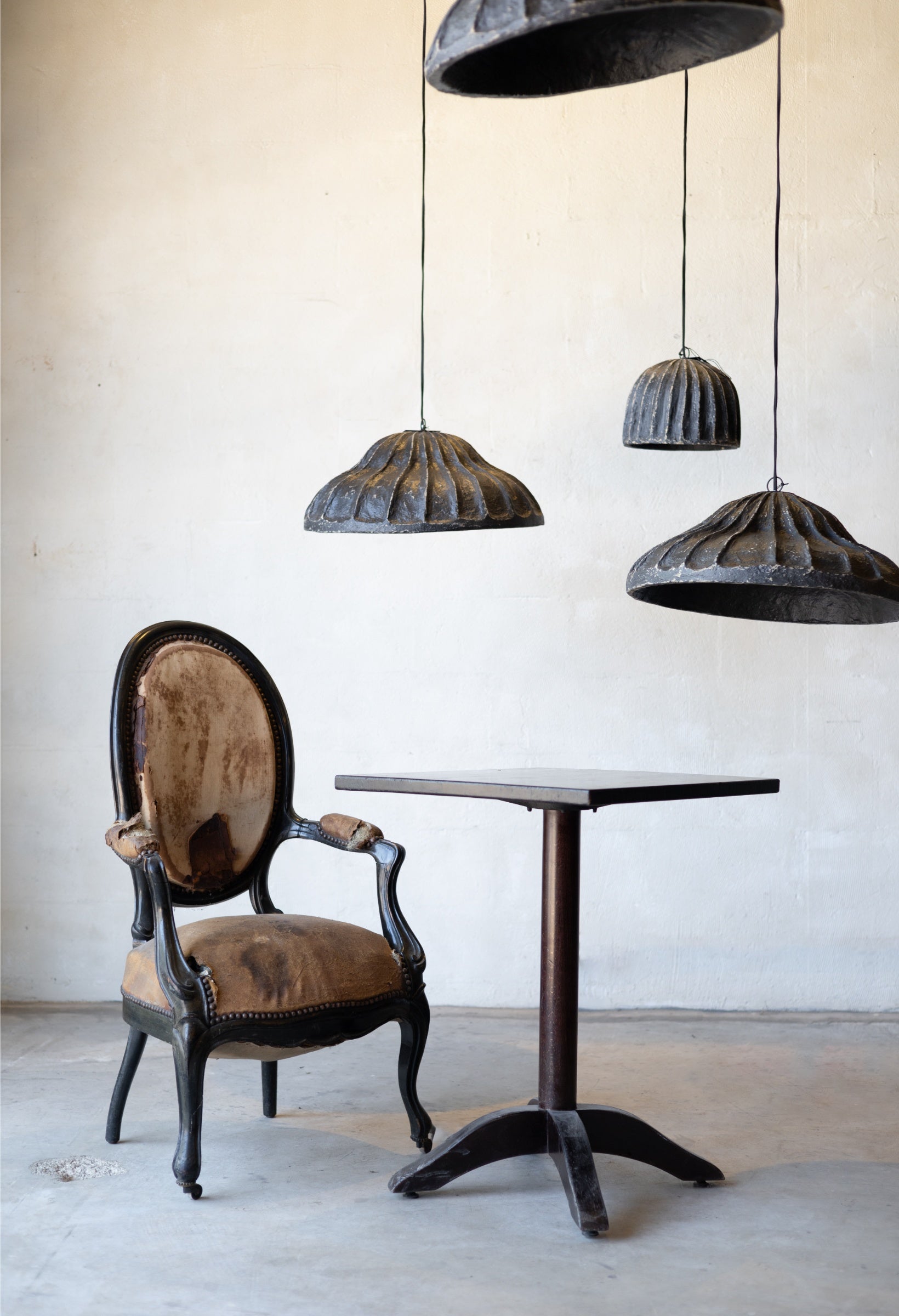 Vintage chair and table with rustic-style pendant lights in a minimalistic setting.