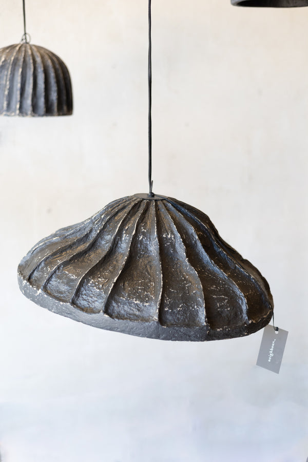 Decorative pendant light with ribbed design on a white background.