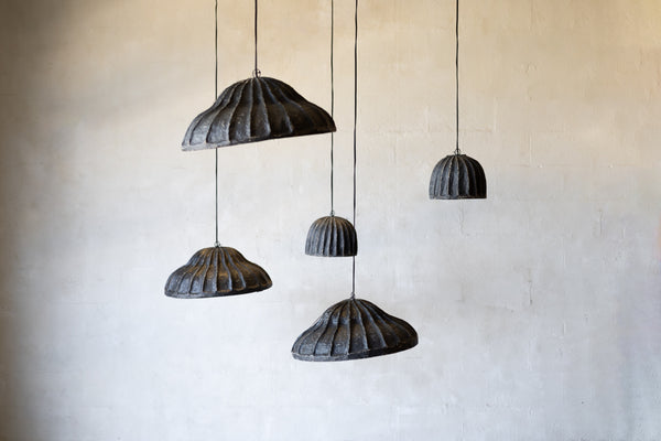 Set of five black pendant lights hanging against a beige wall.