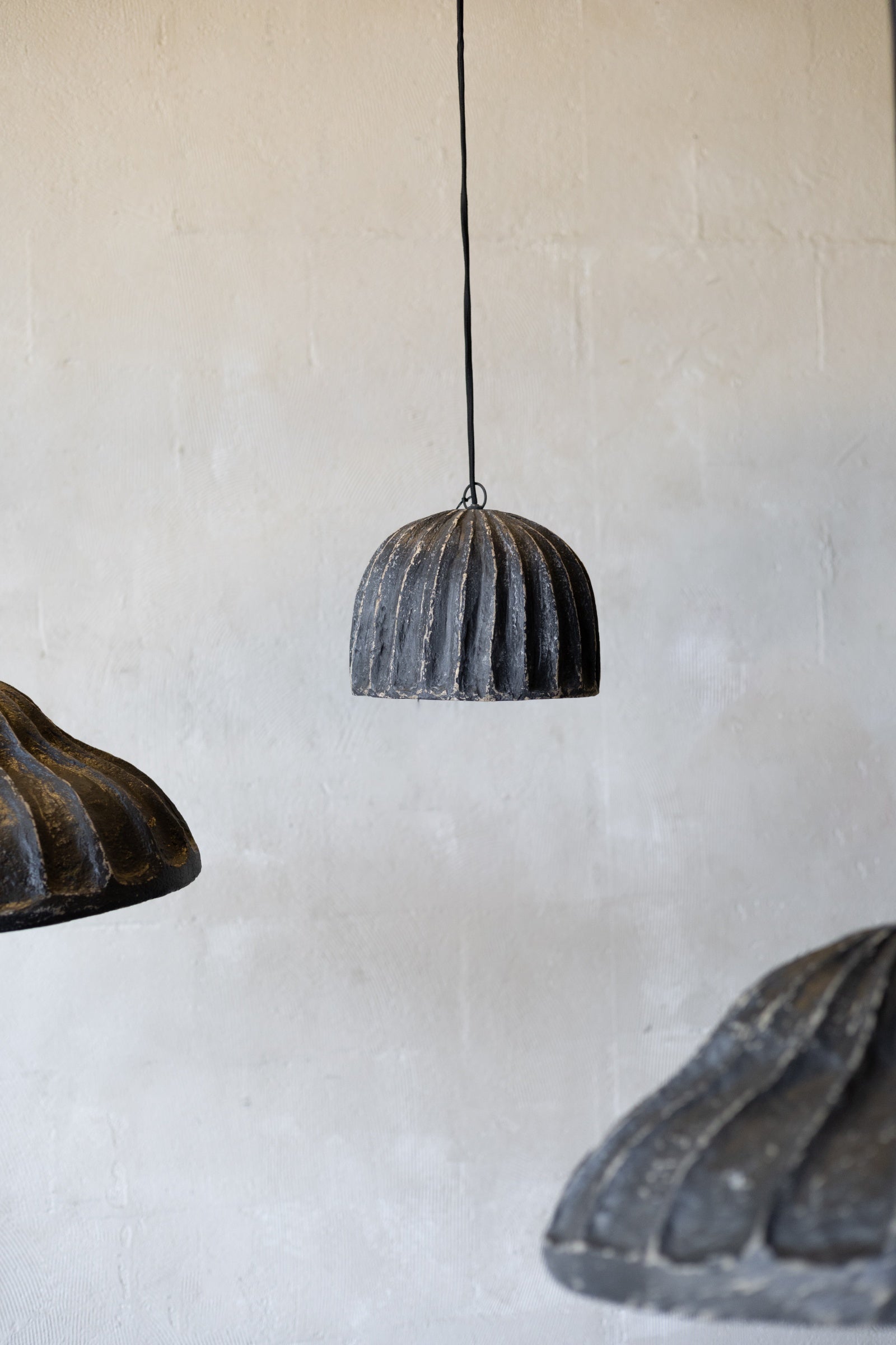 Three rustic pendant lights hanging against a textured wall.