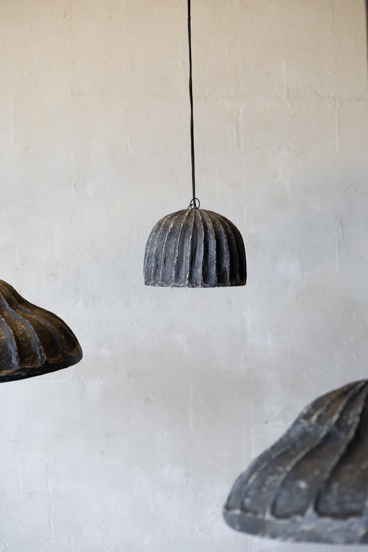 Three rustic pendant lights hanging against a textured wall.