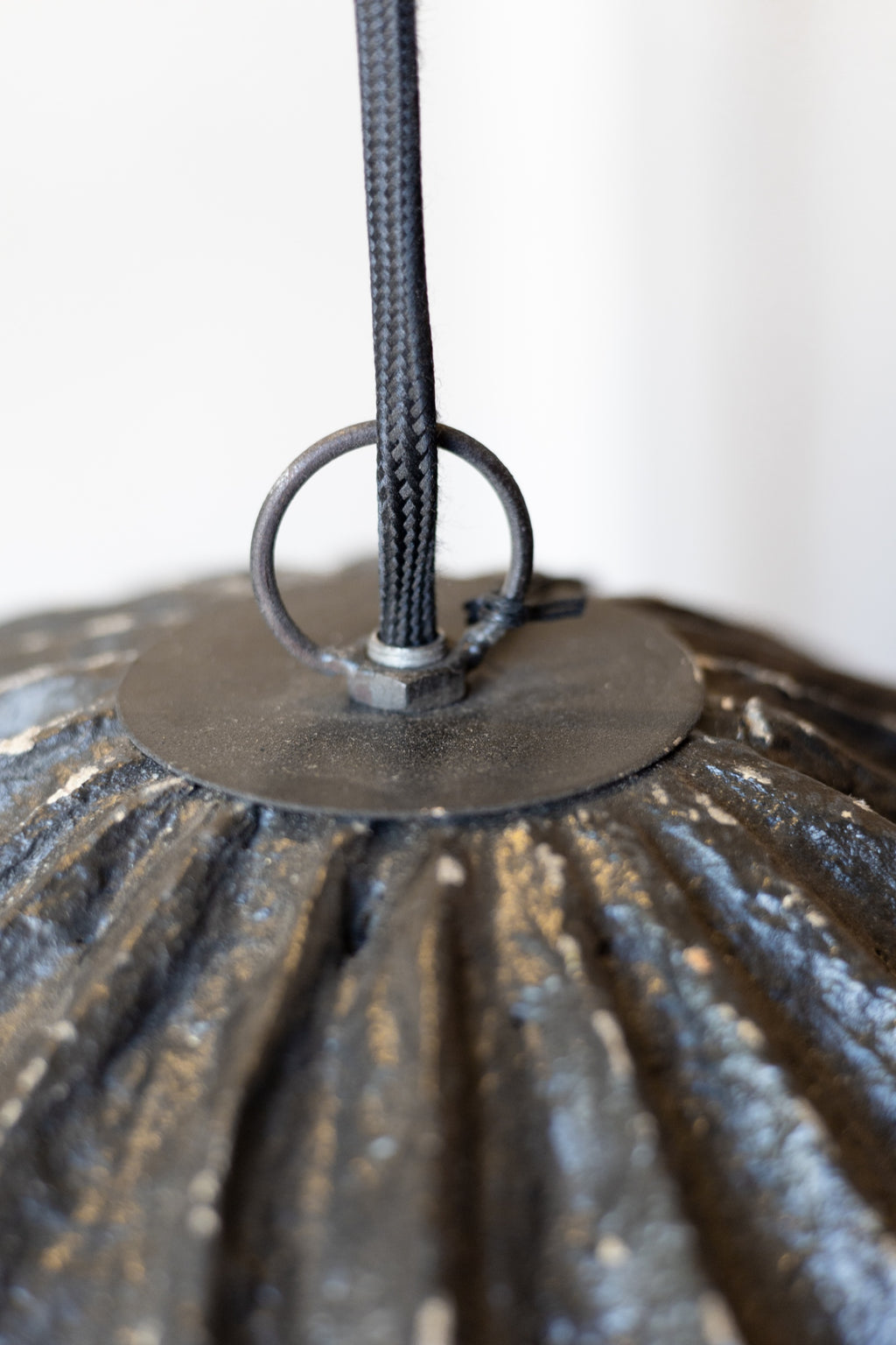 Close-up of a textured papier mache pendant light chord on a white background.
