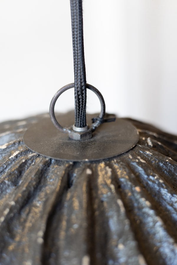 Close-up of a textured papier mache pendant light chord on a white background.