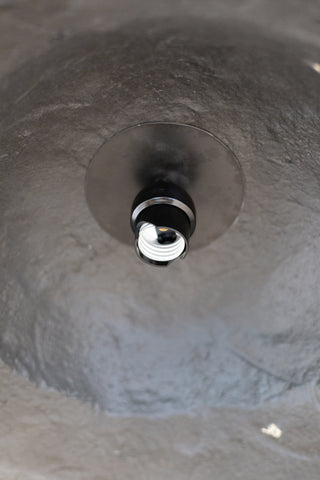 Close-up of a light bulb socket inside a textured black pendant light. 