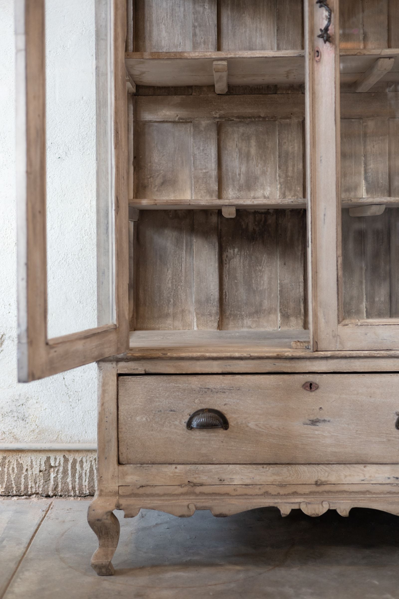 Wooden cabinet with glass doors and a drawer on a neutral background