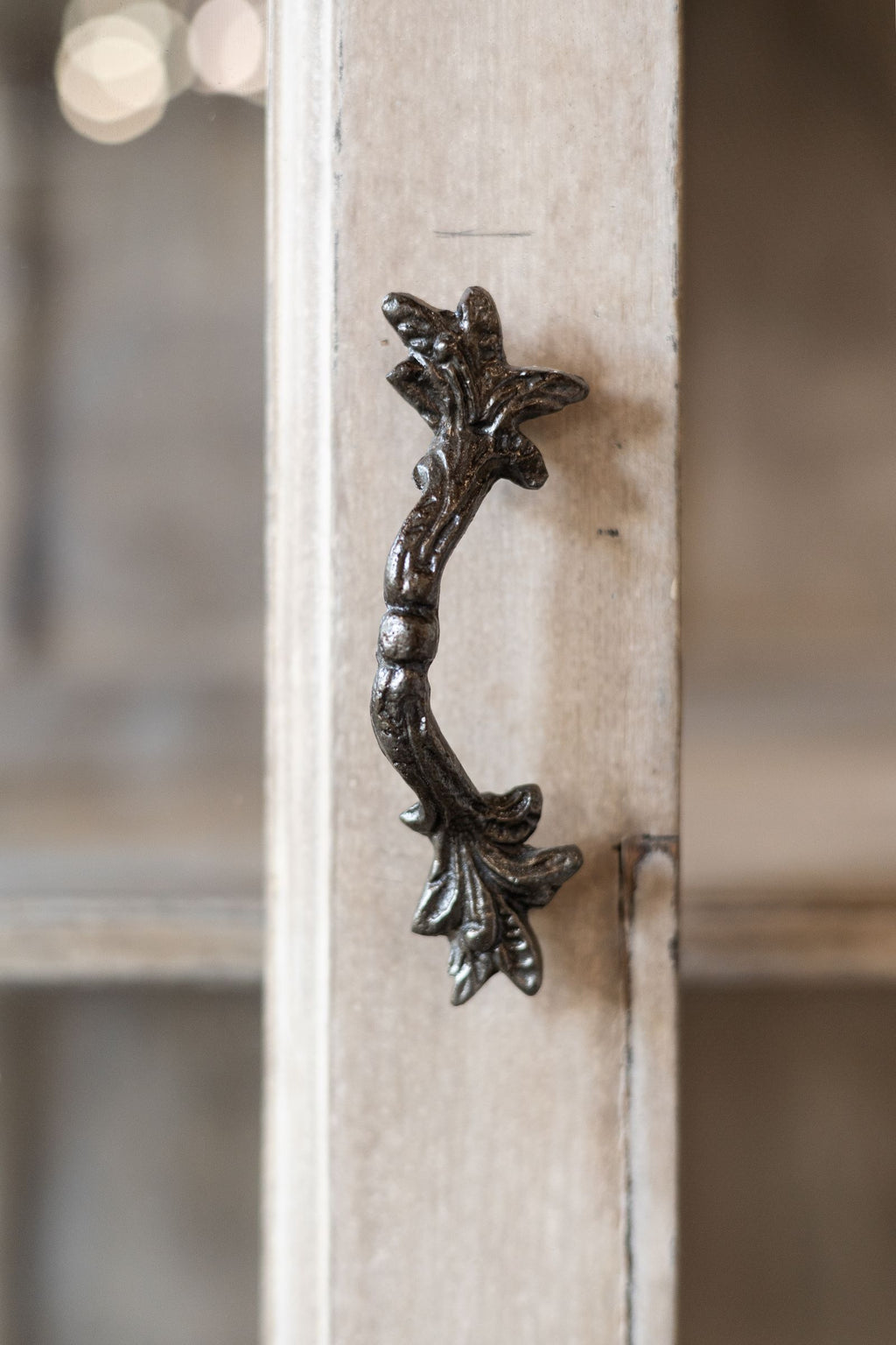 Decorative metal handle on a wooden surface with a blurred background