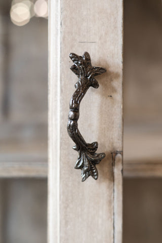 Decorative metal handle on a wooden surface with a blurred background