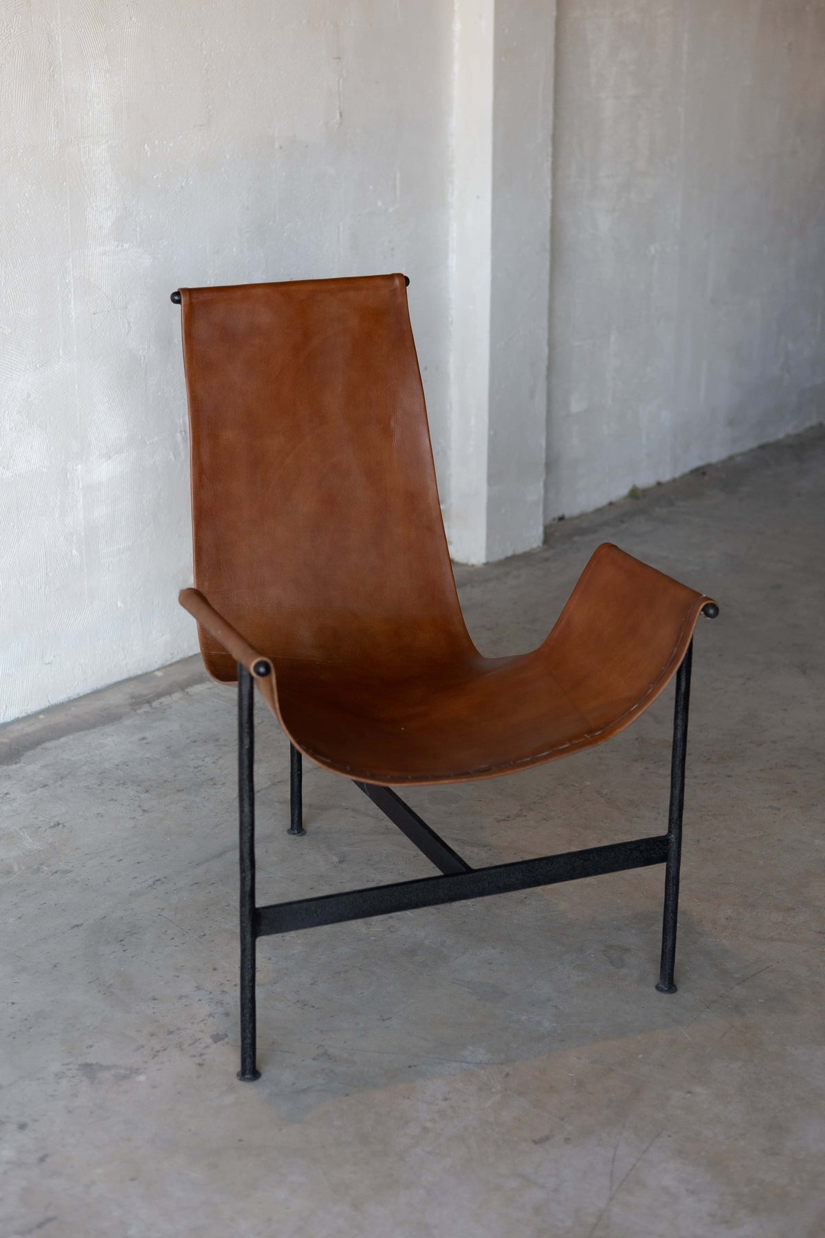 Camel brown leather sling chair with black iron frame.  Main image
