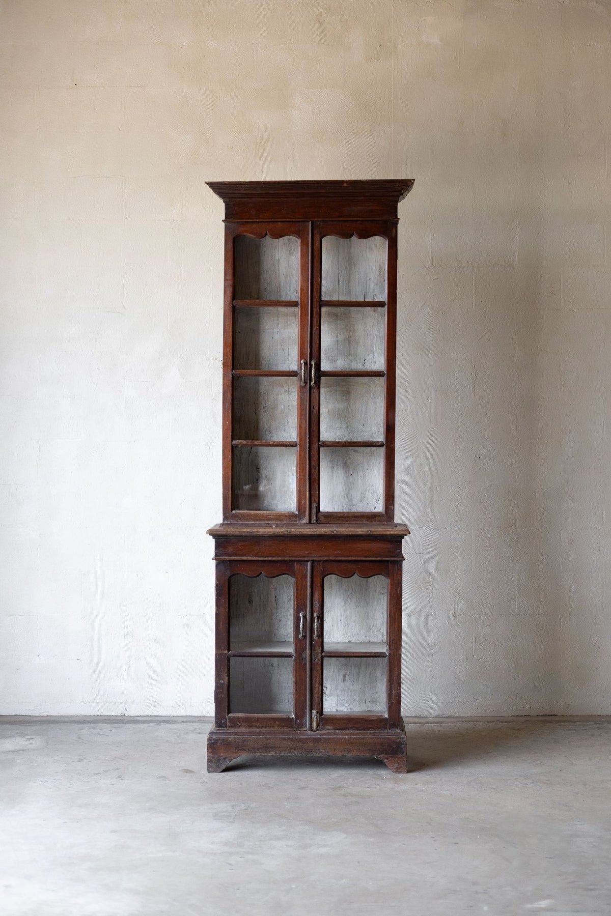 Wooden bookshelf with glass doors against a plain wall. Main image