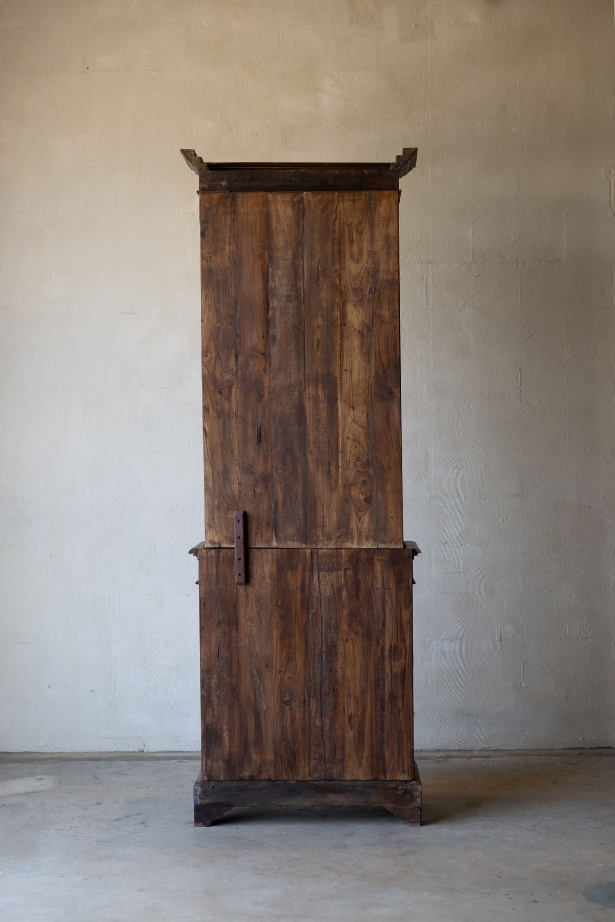 Back of vintage wooden bookcase against a plain wall.