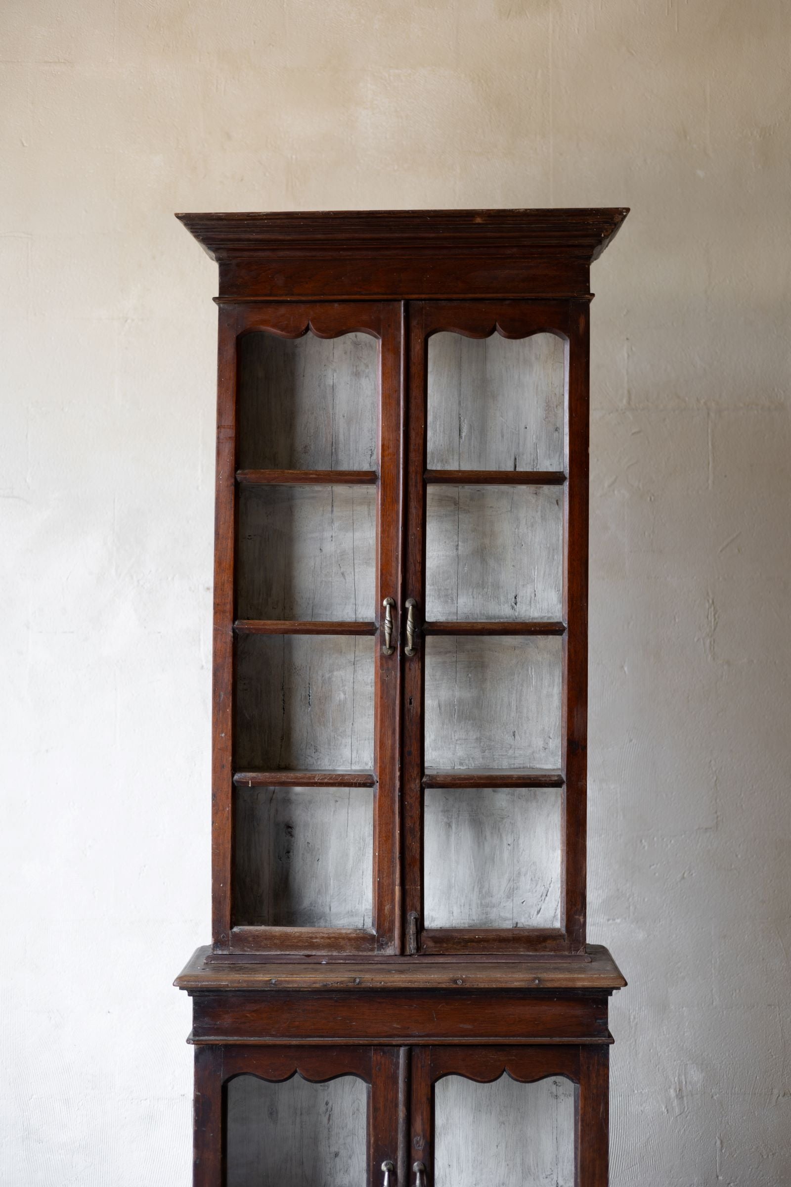 Vintage wooden cabinet with glass doors against a plain wall