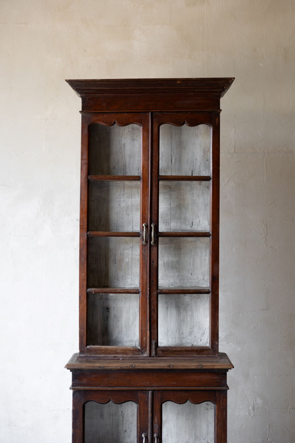 Vintage wooden cabinet with glass doors against a plain wall