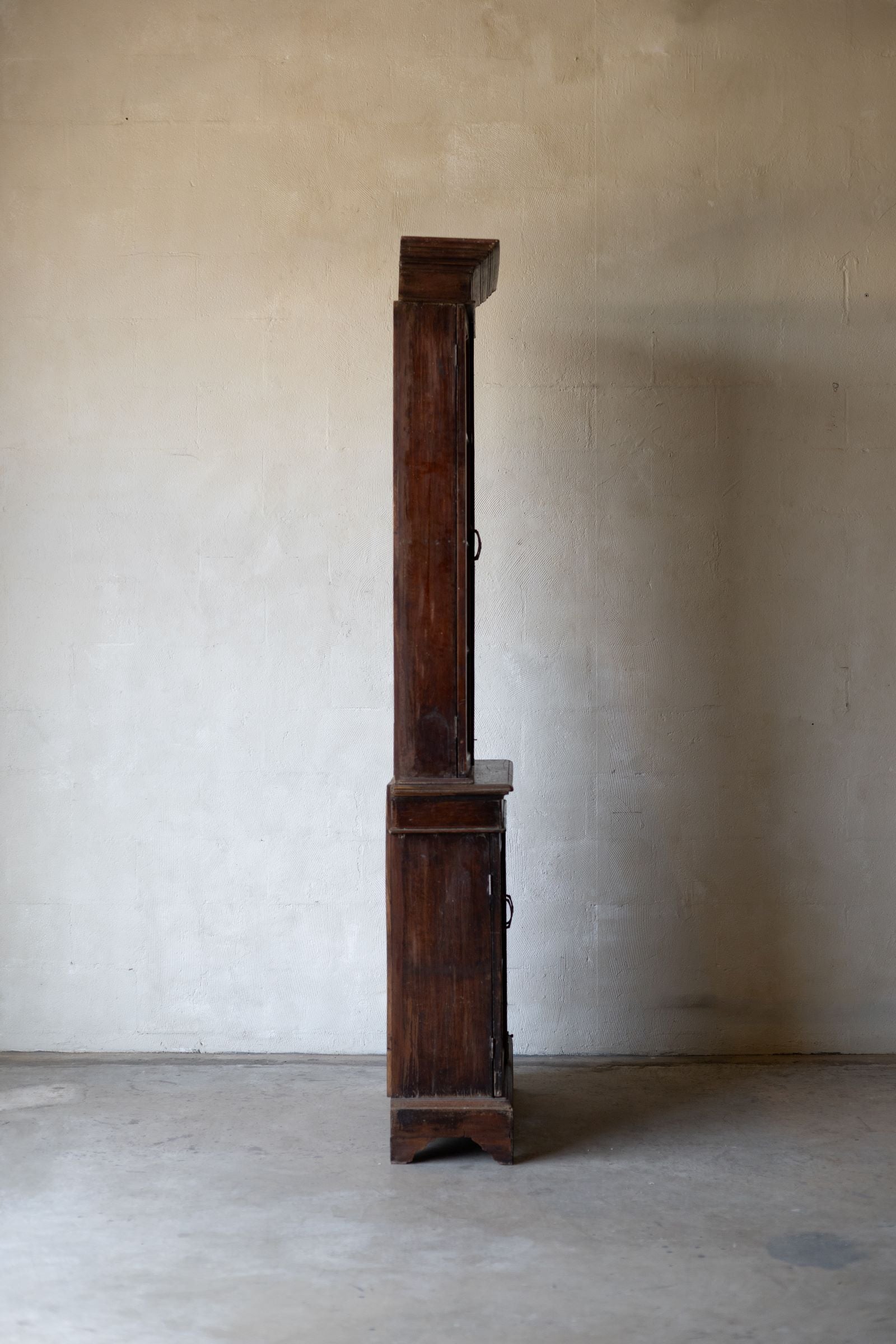 Side profile of wooden bookcase against a plain wall