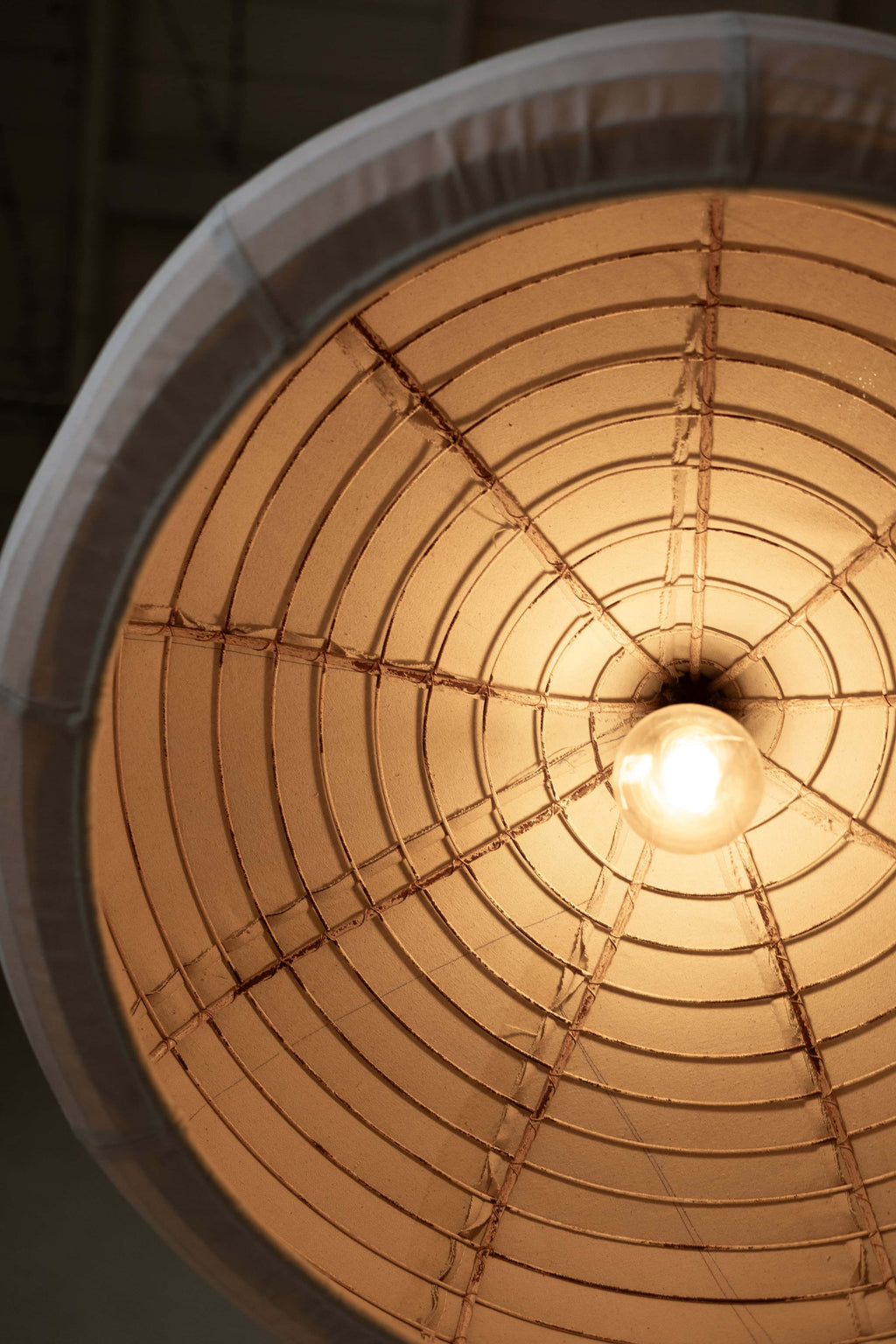 Image showing inside of pendant light's industrial metal frame and warm glow from lightbulb.