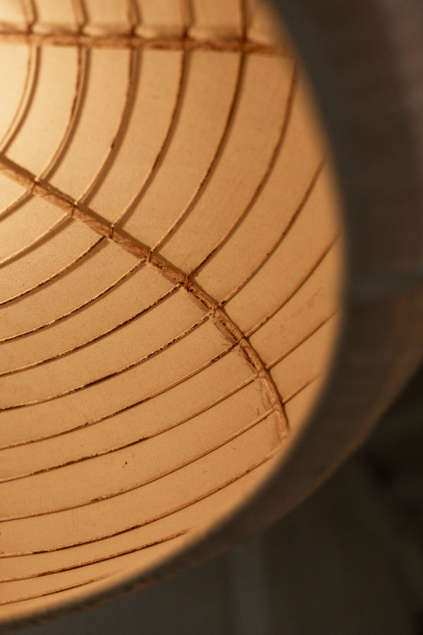 Close up showing inside of pendant light's industrial metal frame and warm glow from lightbulb.