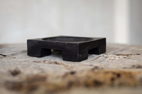 Side view of a black cast iron cigar tray with block leg design.