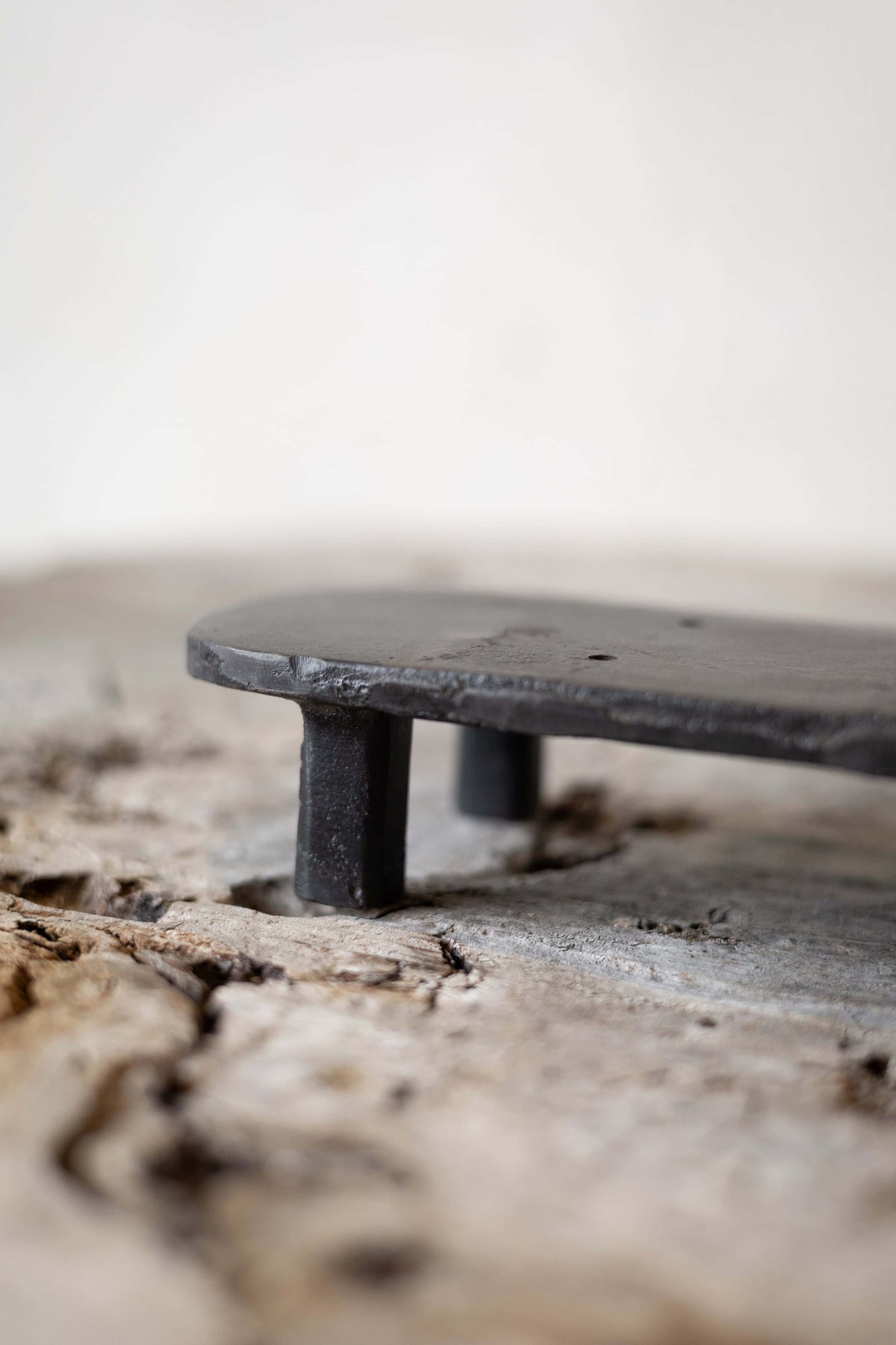 A black, oval cast iron soap stand on a worn wooden surface. Main image