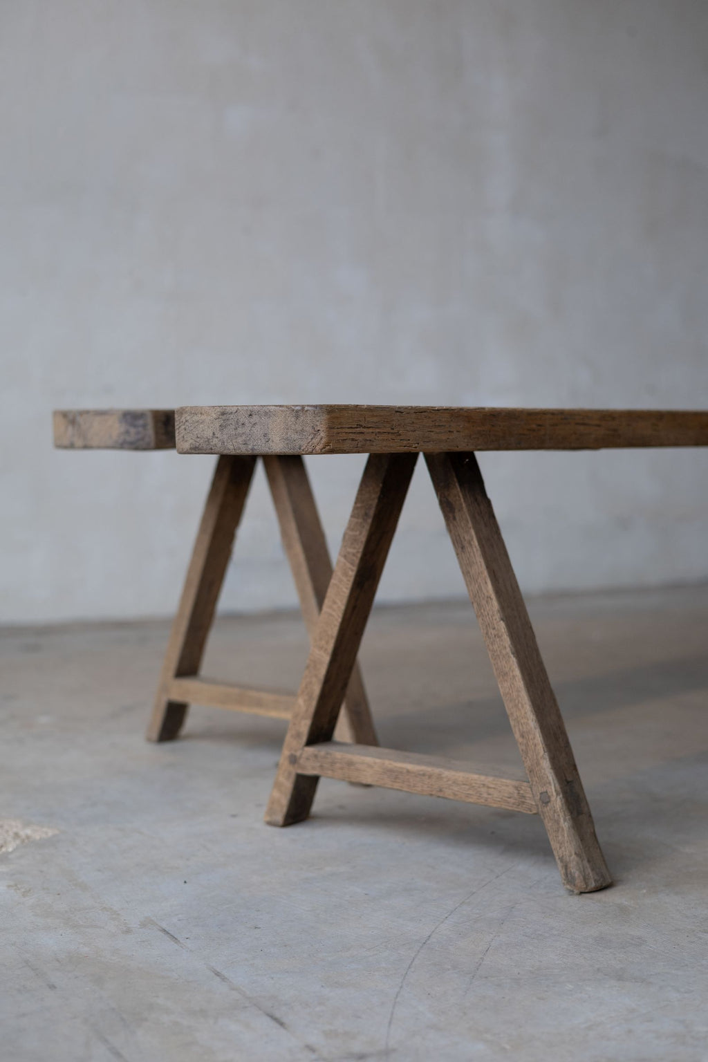 Partial staggered view of two long, thin, wooden dining benches, with simple A-frame.
