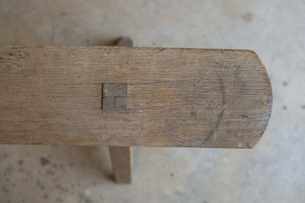 Close-up view of the top of a thin, wooden dining bench, featuring natural, rustic wood finish.
