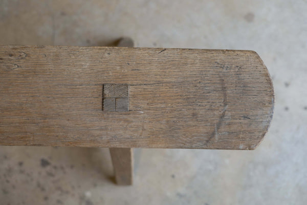 Close-up view of the top of a thin, wooden dining bench, featuring natural, rustic wood finish.