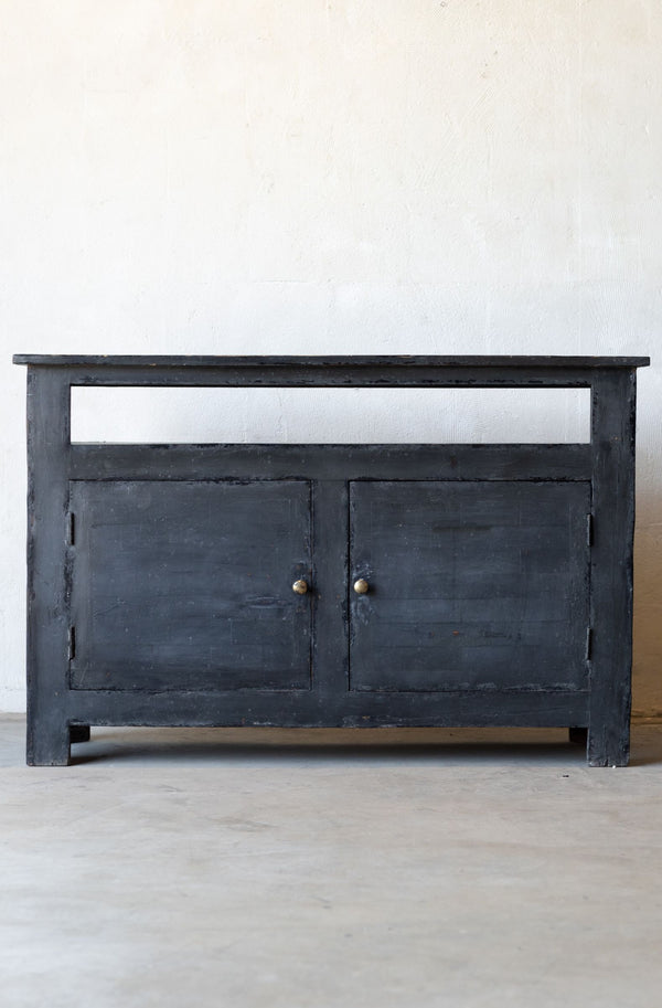 Dark wooden console table with two doors on a light gray floor and white wall background.
