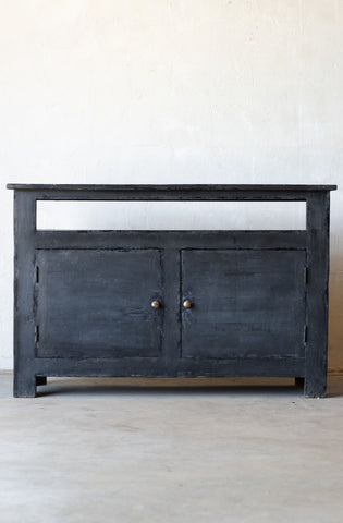 Dark wooden console table with two doors on a light gray floor and white wall background.