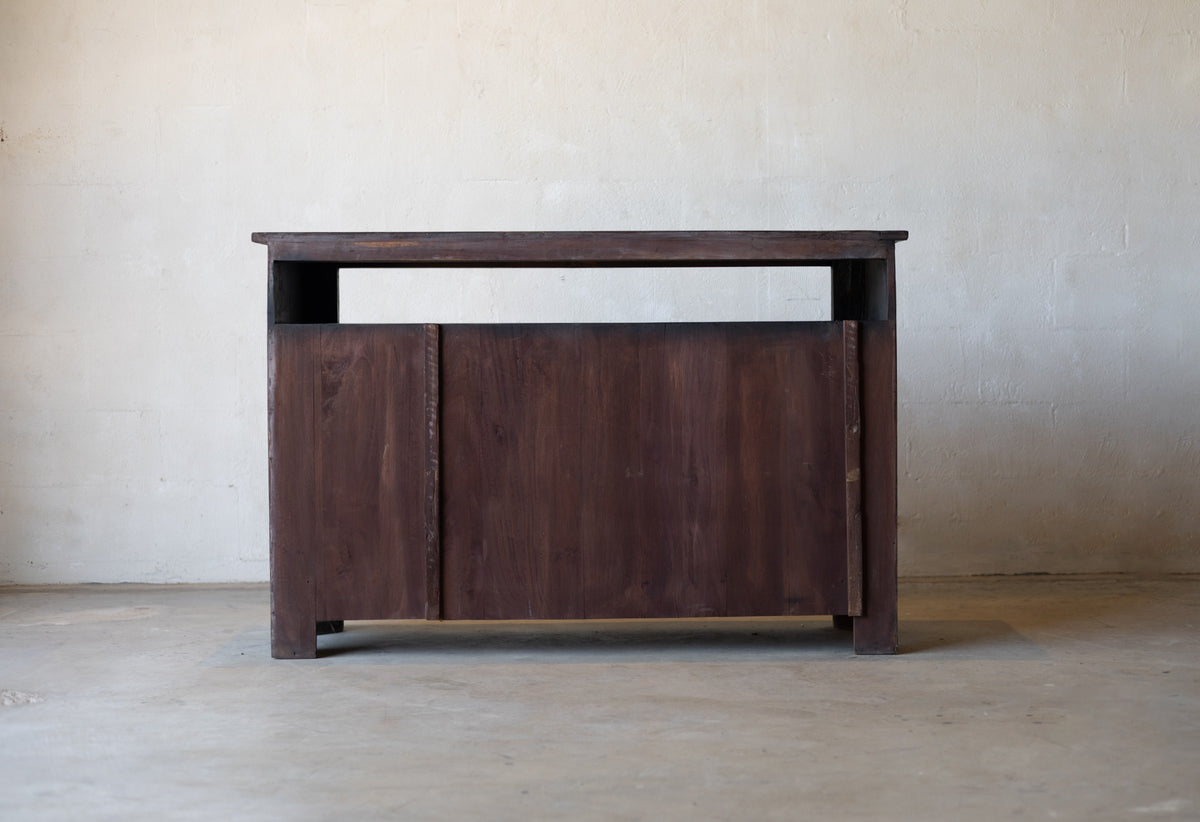Back of wooden sideboard cabinet against a plain wall.